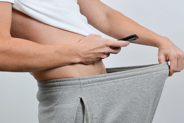 một người đàn ông nhìn xuống quần của mình để thấy dương vật to ra